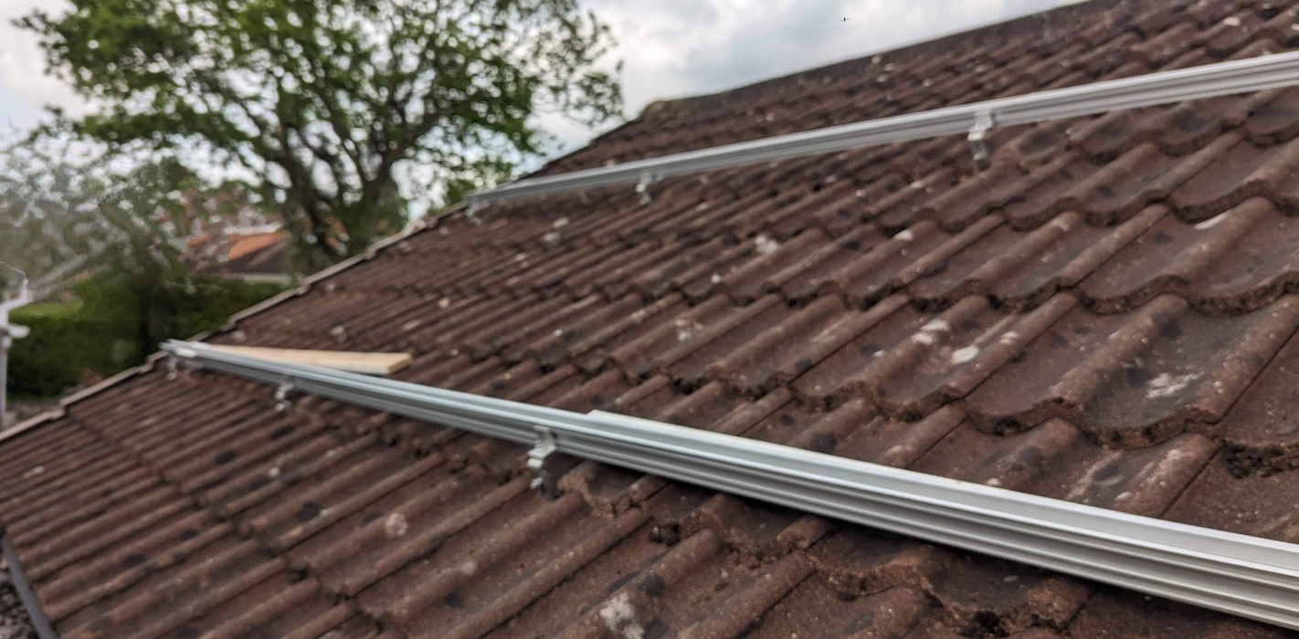 Photograph of a tiled roof with 2 parallel aluminium rails attached to it.