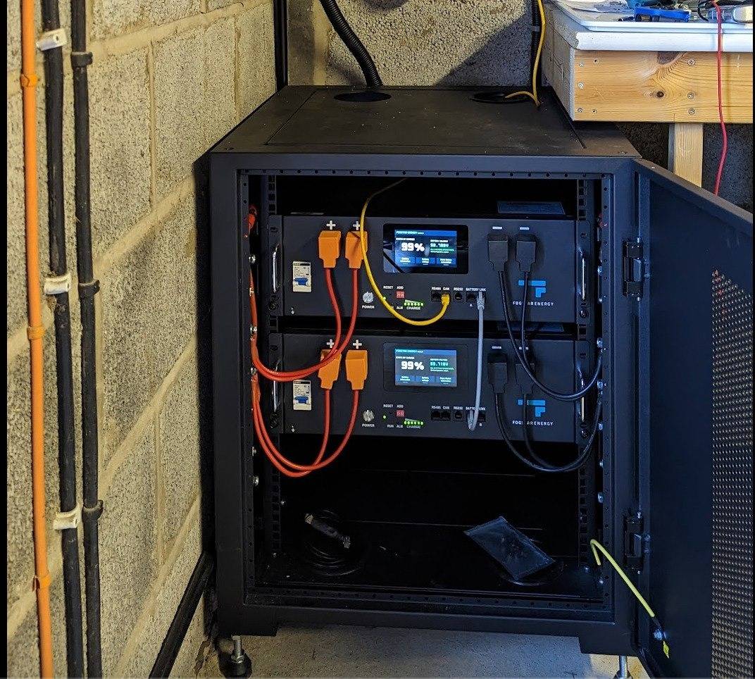 Fogstar Energy server rack with two 5.12kWh battery packs installed, showing orange connectors, BMS screens, and cabling