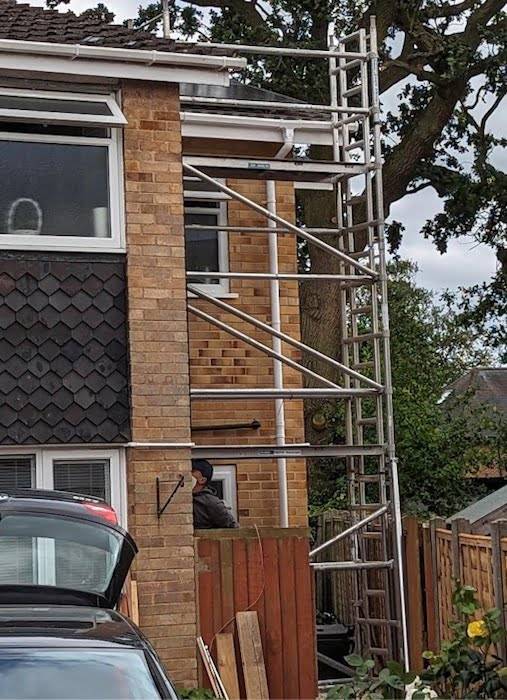 scafolding tower A photograph of a scaffolding tower reaching up to the roof of a two-storey house